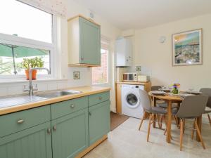 a kitchen with a sink and a table with chairs at Sea View Cottage in Frinton-on-Sea