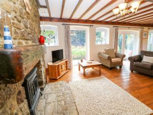 a living room with a stone fireplace and a tv at Coth Skyber in Hayle