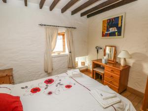 a bedroom with a bed and a desk and a window at Bluebell Cottage in Milford Haven