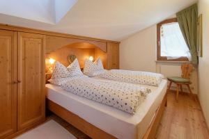 een slaapkamer met een groot bed met een houten hoofdeinde bij Residence Mairhofer in Dobbiaco