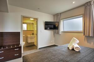 a bed sitting in a bedroom next to a tv at Autoline Queenstown Motel in Queenstown