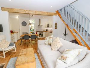 a living room with a white couch and a staircase at Cragside Cottage in Hebden Bridge