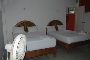 two beds in a room with a fan at Hospedaje Papagrande in Homún