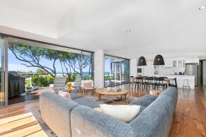 ein Wohnzimmer mit einem Sofa und einem Tisch sowie eine Küche in der Unterkunft Stunning Seaviews, Sunshine Beach in Sunshine Beach