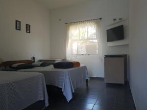 a room with two beds and a tv and a window at Vargas Peruibe Hotel in Peruíbe