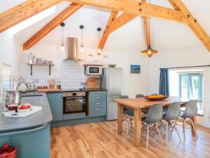 a kitchen with blue cabinets and a wooden table at Manor House Barn in Camelford