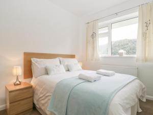 a white bedroom with a large bed with a window at Rock Cottage in Keswick