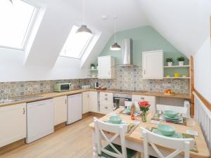 a kitchen with white cabinets and a wooden table and chairs at The Forge in Winscombe