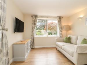 a living room with a couch and a window at Cherry Tree Lodge in Axminster