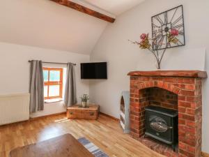 a living room with a brick fireplace and a tv at Old Hall Barn 3 in Church Stretton