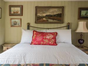 a bedroom with a white bed with a red pillow at Crows Cabin in Gloucester