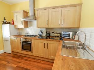 a kitchen with wooden cabinets and a stainless steel sink at Molly's Cottage in Grange Over Sands