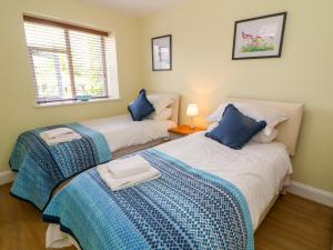 a bedroom with two beds with blue and white sheets at Molly's Cottage in Grange Over Sands
