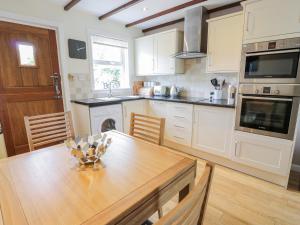 a kitchen with a wooden table and a dining room at Grebe Cottage in Oban