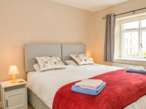 a bedroom with a large white bed with a red blanket at Cutlers Cottage in Matlock