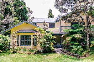 a yellow house with a garden in front of it at Kilauea Lodge and Restaurant in Volcano