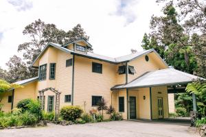 ein gelbes und weißes Haus mit einem Dach in der Unterkunft Kilauea Lodge and Restaurant in Volcano