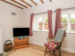 a living room with a tv and a chair at Cutlers Cottage in Matlock