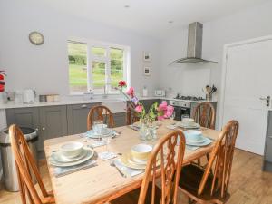 uma cozinha e sala de jantar com uma mesa de madeira e cadeiras em Ingledene em Highpeak Junction