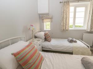 a bedroom with two beds and two windows at Ingledene in Highpeak Junction