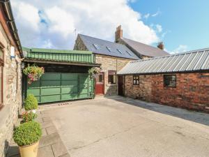 un garaje con una puerta roja y un edificio de ladrillo en Ferngrove Cottage, en Bishop Auckland