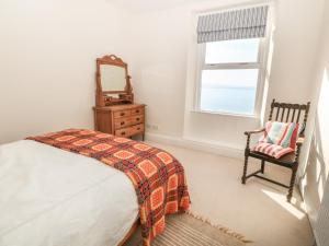 ein Schlafzimmer mit einem Bett, einem Stuhl und einem Fenster in der Unterkunft 11 Marine Terrace in Criccieth