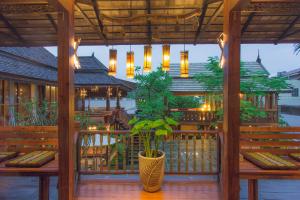 eine Veranda mit Bänken und eine Vase mit Pflanze in der Unterkunft Pao Come Boutique House in Chiang Mai