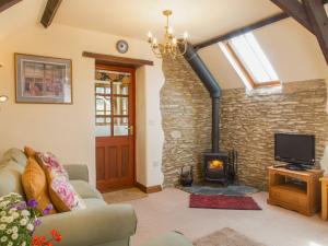 a living room with a fireplace and a tv at The Coach House in Kingsbridge