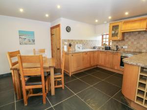 a kitchen with wooden cabinets and a table and chairs at Dysynni in Tywyn