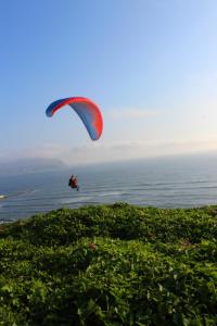 a person flying a parachute over the water at KACLLA, The Healing Dog Hostel in Lima