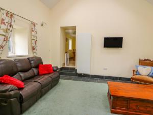 a living room with a brown leather couch and a tv at Hen Brynbedw in Llanybydder