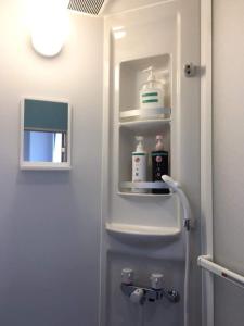 a white refrigerator with medicines on a shelf in a bathroom at Sakai Guest House AMAMI（堺ゲストハウス奄美） in Setouchi