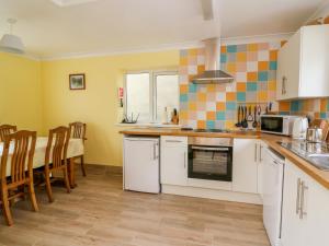 a kitchen with white cabinets and a table with chairs at Hen Brynbedw in Llanybydder