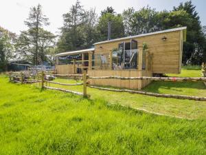 eine Holzhütte auf einem Feld mit einem Zaun in der Unterkunft High Rigg Shepherd's Retreat in Brampton