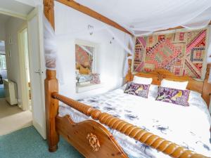 a bedroom with a wooden bed with a canopy at Dyfi Cottage in Machynlleth