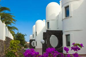 a white building with purple flowers in front of it at Apartamentos Tabaiba in Costa Teguise