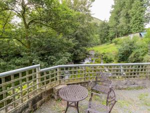 a table and two chairs sitting next to a fence at Dyfi Cottage in Machynlleth