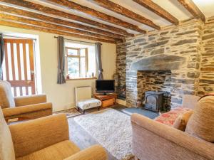 a living room with a stone fireplace and a tv at Dyfi Cottage in Machynlleth