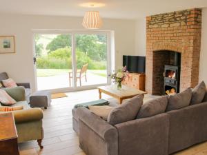 a living room with a couch and a fireplace at The Old Farmhouse, Upper Pitts in Knighton