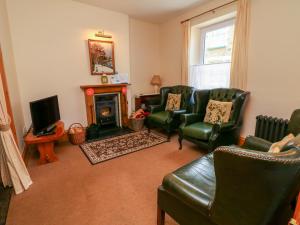a living room with leather chairs and a fireplace at Comers in Ilfracombe