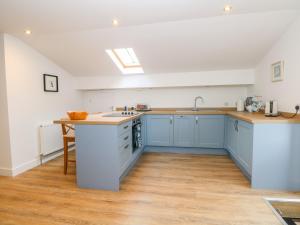 uma grande cozinha com armários azuis e um lavatório em The Croft em Chorley