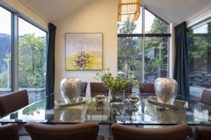 a dining room with a glass table and windows at Lago Infinito by Sotheby's Luxury Rental Homes in Queenstown