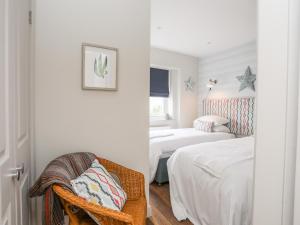 a room with two beds and a chair in it at Braid Apartment in Trearddur