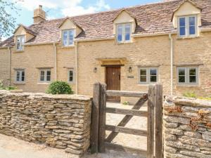 a brick house with a wooden gate and a stone wall at Easter Cottage in Burford