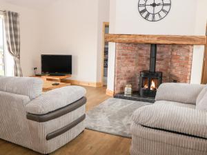 a living room with two chairs and a fireplace at Mandarin Cottage in Melton Mowbray