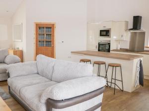 a living room with a couch and a kitchen at Mandarin Cottage in Melton Mowbray