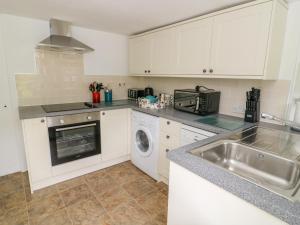 a kitchen with a sink and a washing machine at Church Farm Cottage in Skipton