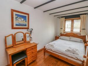 ein Schlafzimmer mit einem Bett, einer Kommode und einem Spiegel in der Unterkunft Cowslip Cottage in Milford Haven