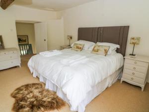 a bedroom with a large white bed with a dog laying on the floor at Church Farm Cottage in Skipton