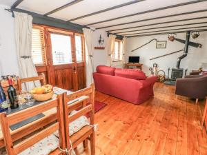 een woonkamer met een rode bank en houten vloeren bij Cowslip Cottage in Milford Haven